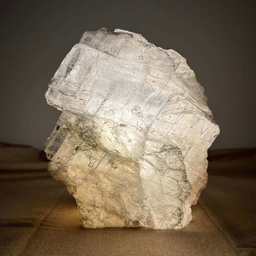 Krystalstruktur af gennemsigtigt, lysende mineral på en brun overflade.