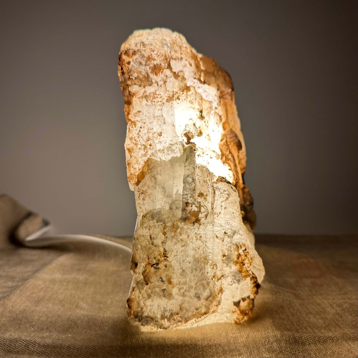 Rustik stenlampe oplyst i dæmpet lys, der fremhæver dens naturlige teksturer og farver.