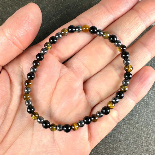 Armbånd med perler af sort og gylden farve lagt i en håndflade.