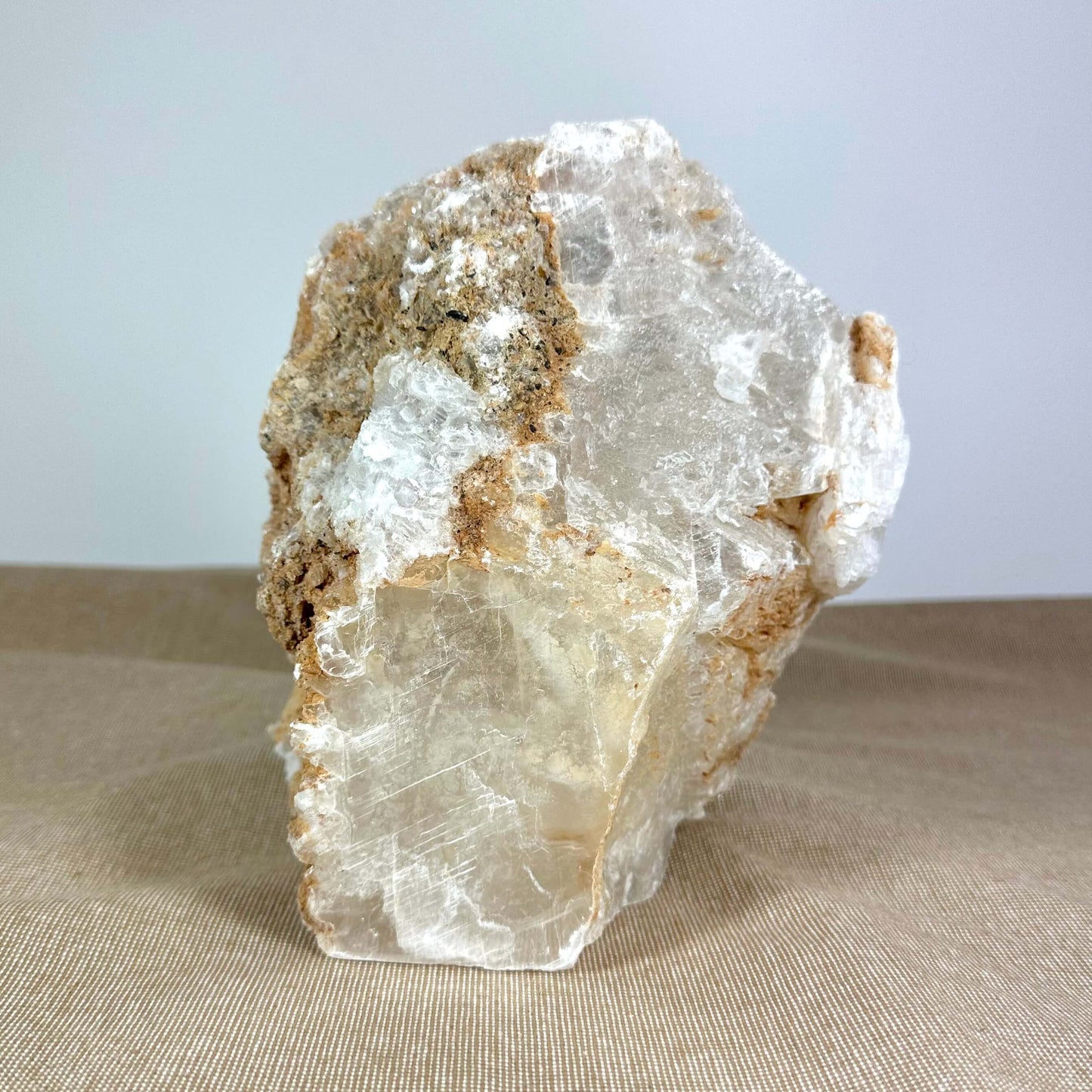 Klar krystal og jordfarvet sten på beige overflade.