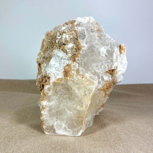 Klar krystal og jordfarvet sten på beige overflade.