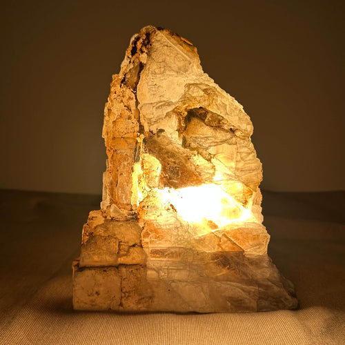 En stenet lampe, der lyser indefra, skaber en varm glød i et mørkt rum.