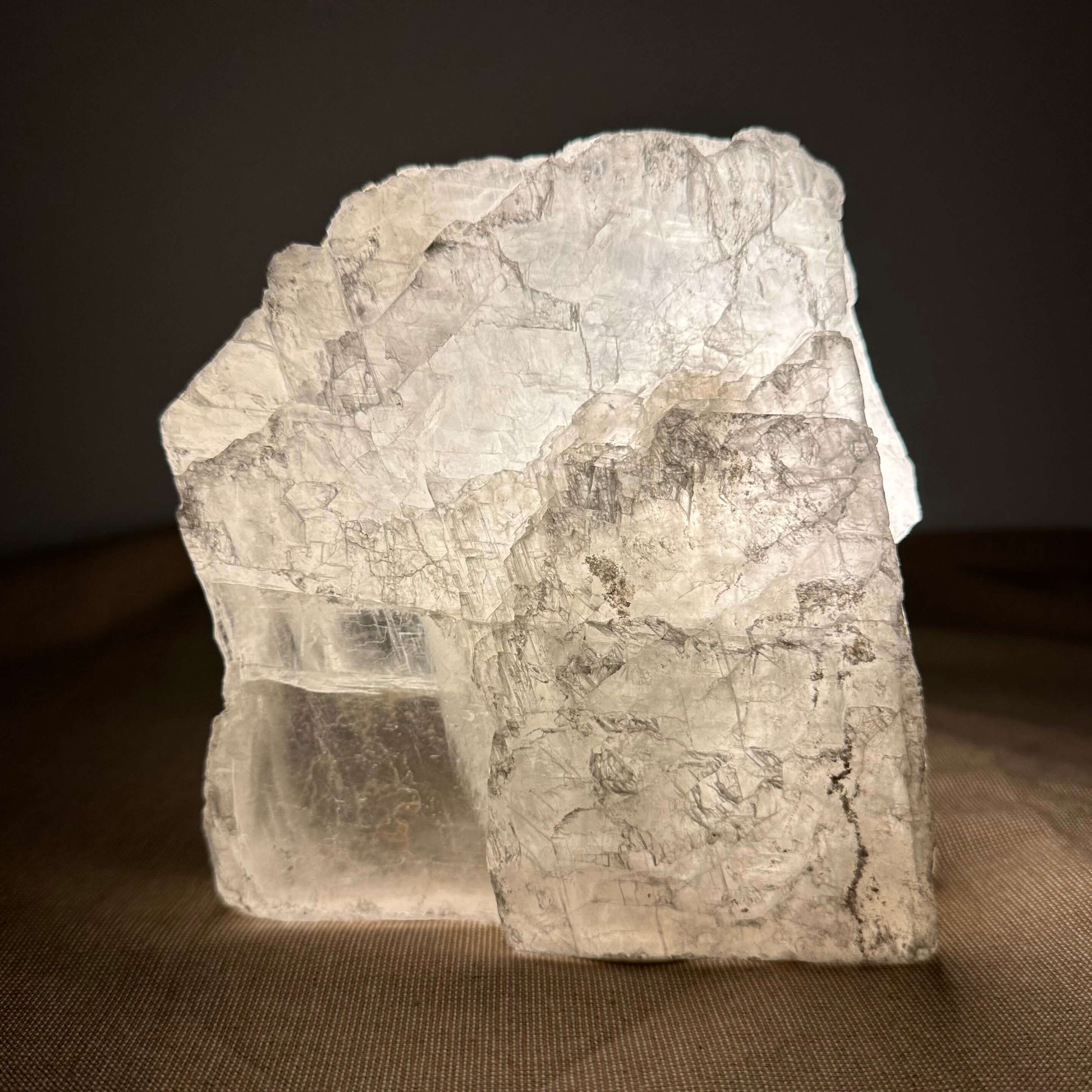 Klar krystal på en brun overflade med mørk baggrund.