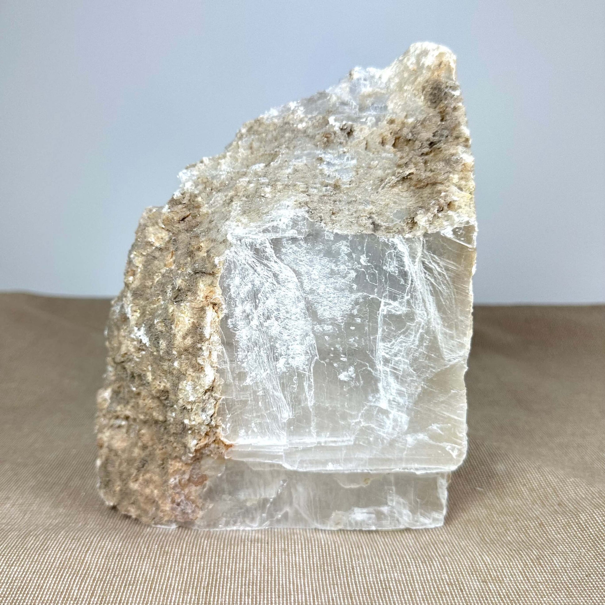 En stor krystalblok med en ru, brun overflade øverst og klare glatte flader nedenfor.