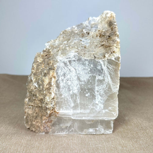 En stor krystalblok med en ru, brun overflade øverst og klare glatte flader nedenfor.