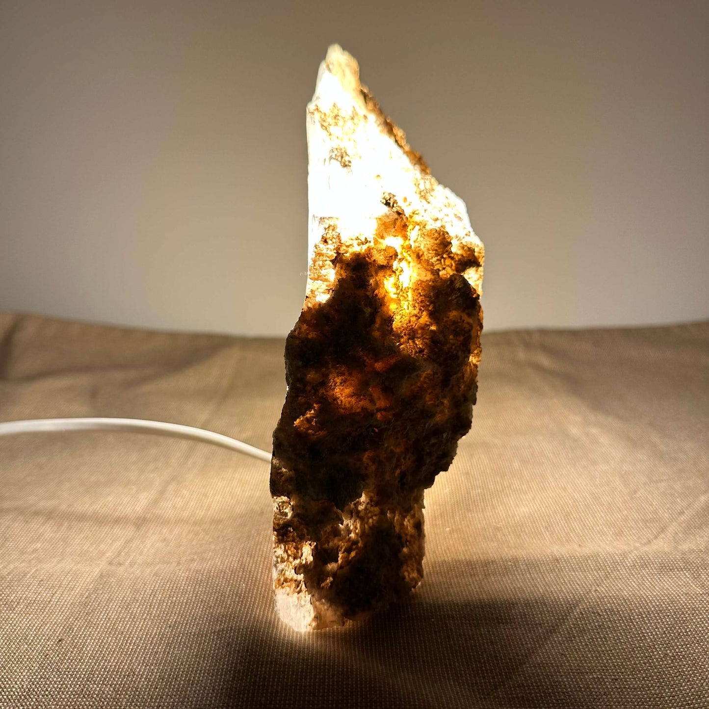 En oplyst stenlampe med rustik overflade står på et bord med en varm lysglød.