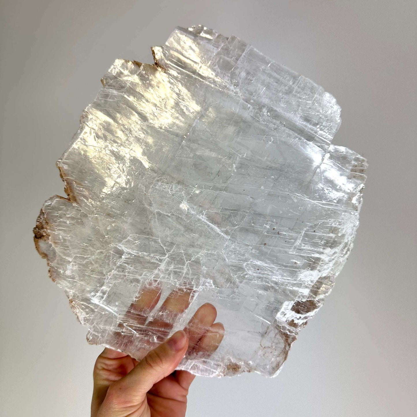 Klar krystal holdt i hånden mod en lys baggrund.