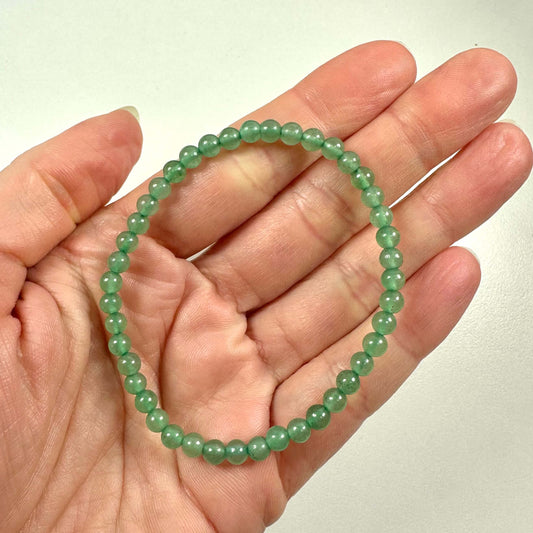 Grønt aventurin armbånd med små polerede perler i en åben håndflade