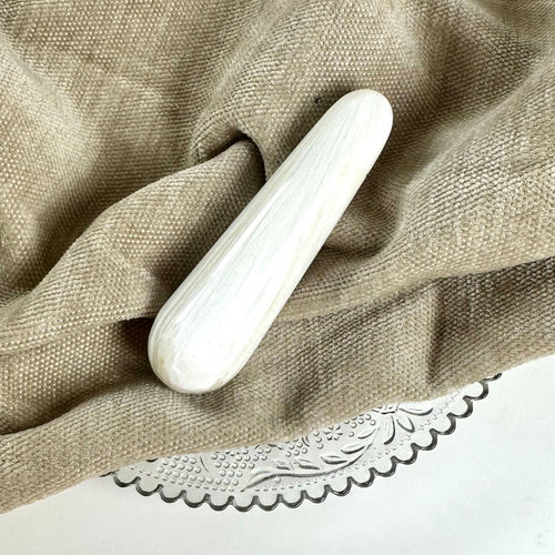 Scolesit stav placeret på en beige tekstil og dekorativ glasplade.