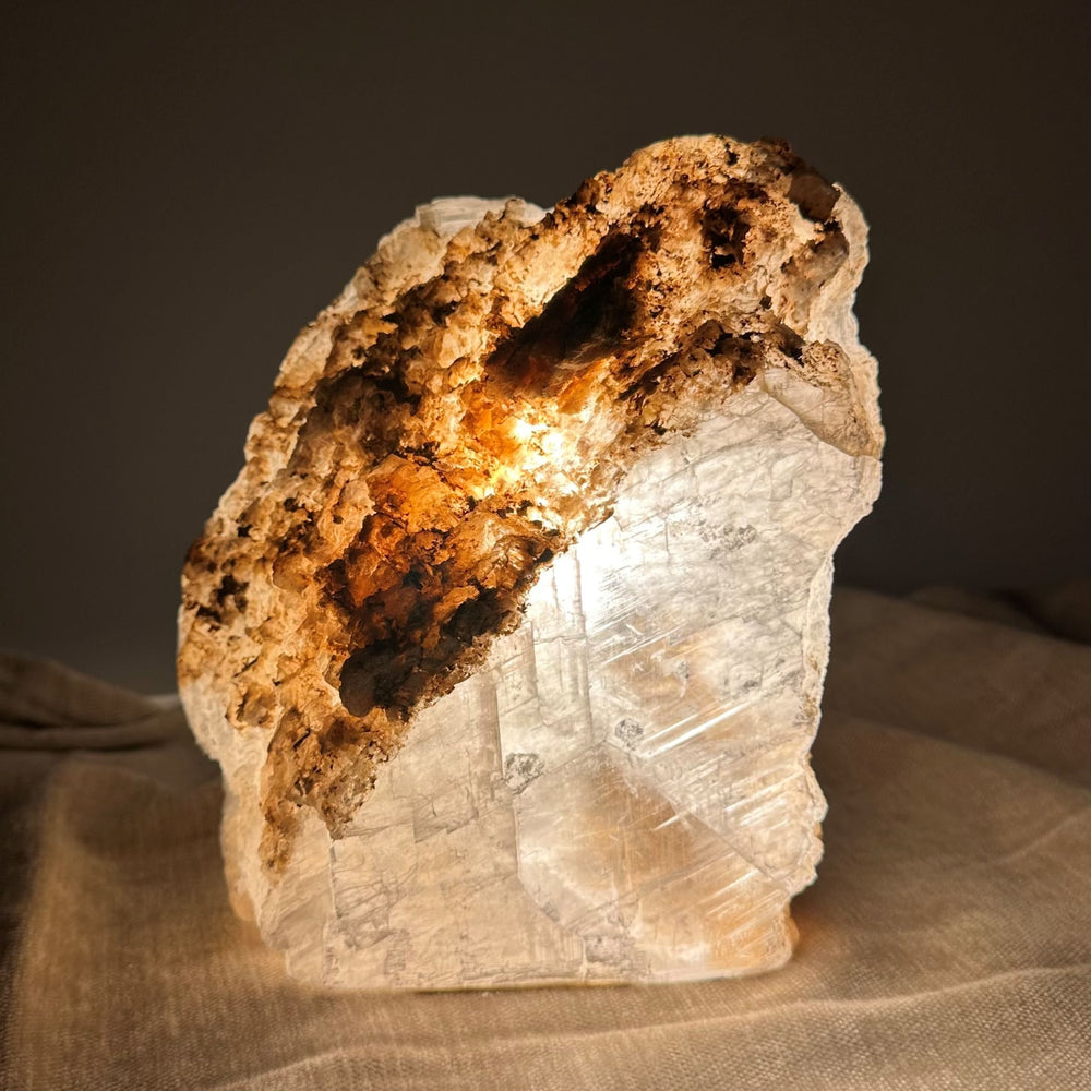 Mexicansk Selenit lampe nr 28, der lyser varmt indefra, placeret på et blødt stofunderlag.