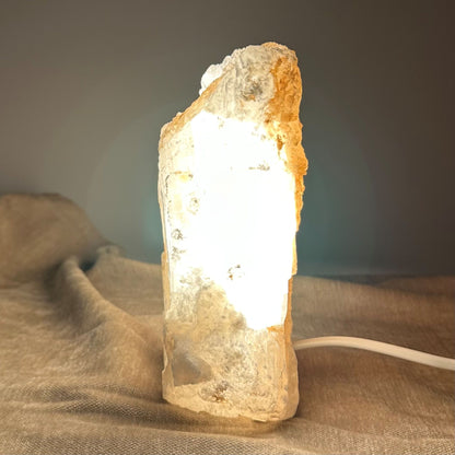 Mexicansk Selenit lampe nr 25 lyser varmt op på en tekstureret overflade, med ledning synlig for tilslutning.