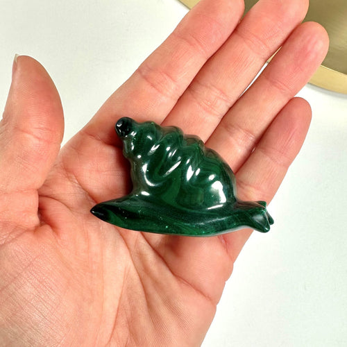 Hånd holder en grøn Malakit Snegl skulptur.