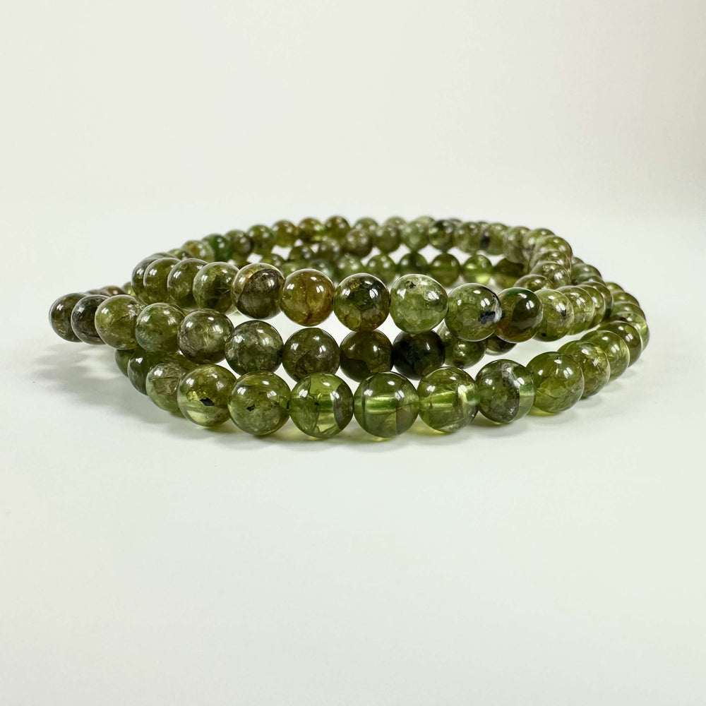Grønne Peridot armbånd på hvid baggrund, lavet af kugleformede peridotsten i tæt formation.