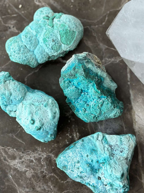Chrysocolla med Malakit sten på en mørk overflade, hvor deres blågrønne nuancer tydeligt ses.