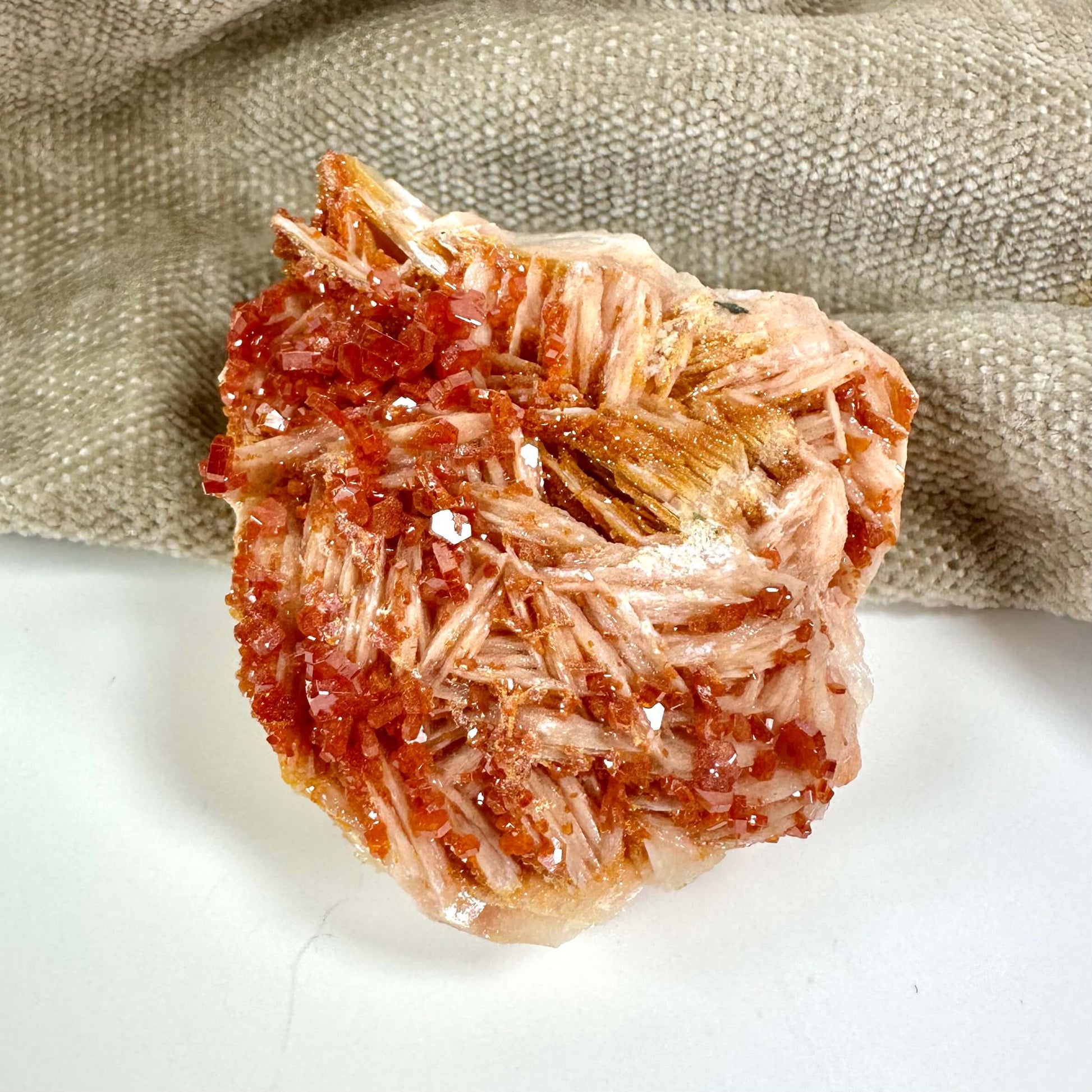 Rød, krystallinsk klynge af mineraler på en grå baggrund.