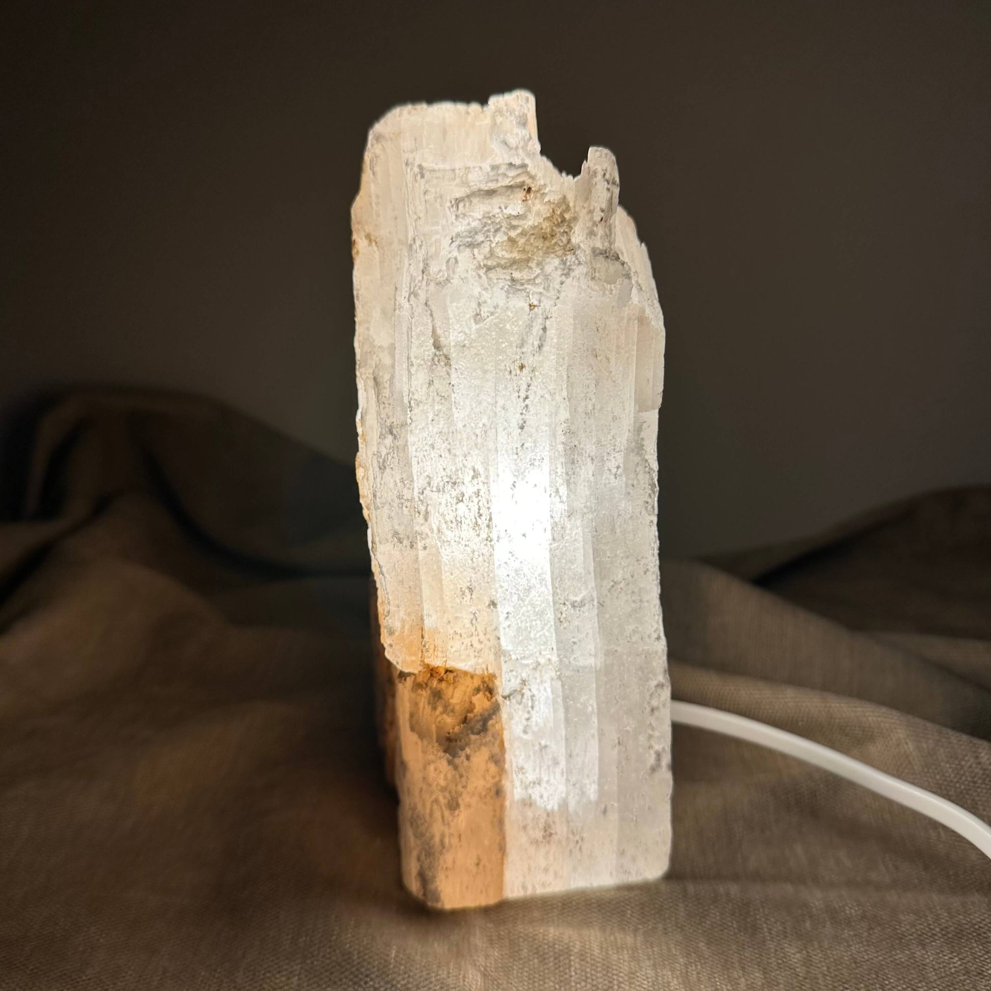 Selenitlampe lyser blødt på en beige overflade i dæmpet rum.