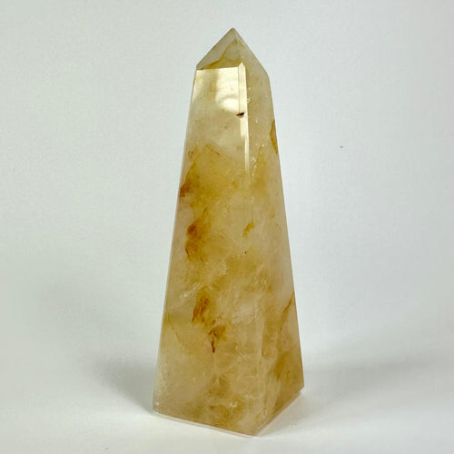 Golden healer obelisk med gyldne toner stående mod en hvid baggrund.