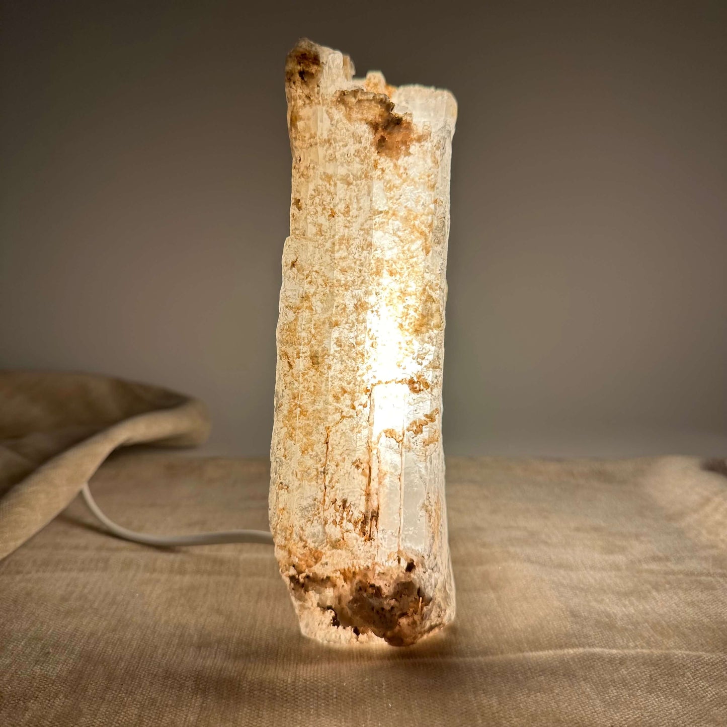 Mexicansk Selenit lampe nr 26 lyser op på en stofbelagt overflade i dæmpet belysning.
