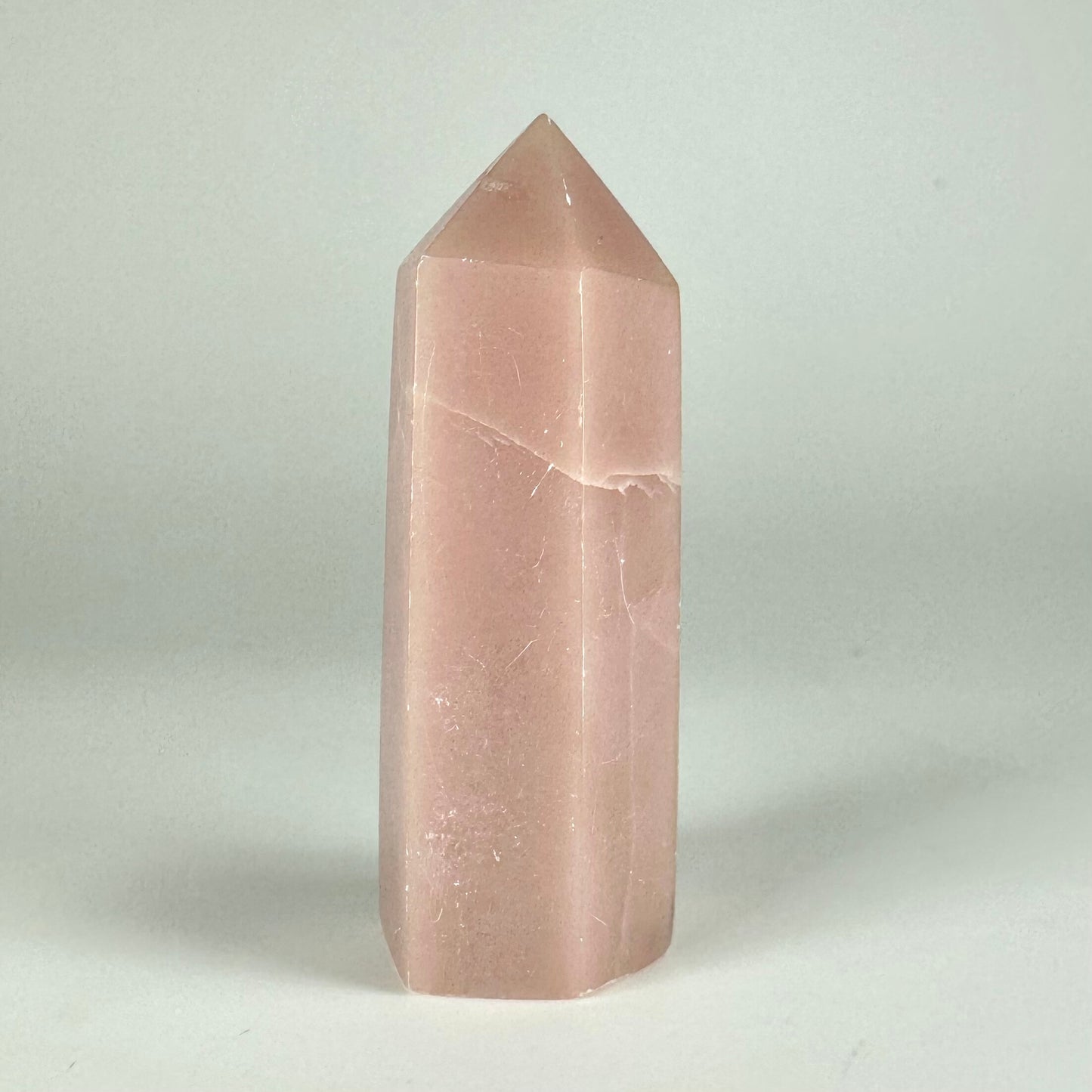 Pink opal tårn mod en grå baggrund, der fremhæver dets bløde nuancer og glatte overflade.