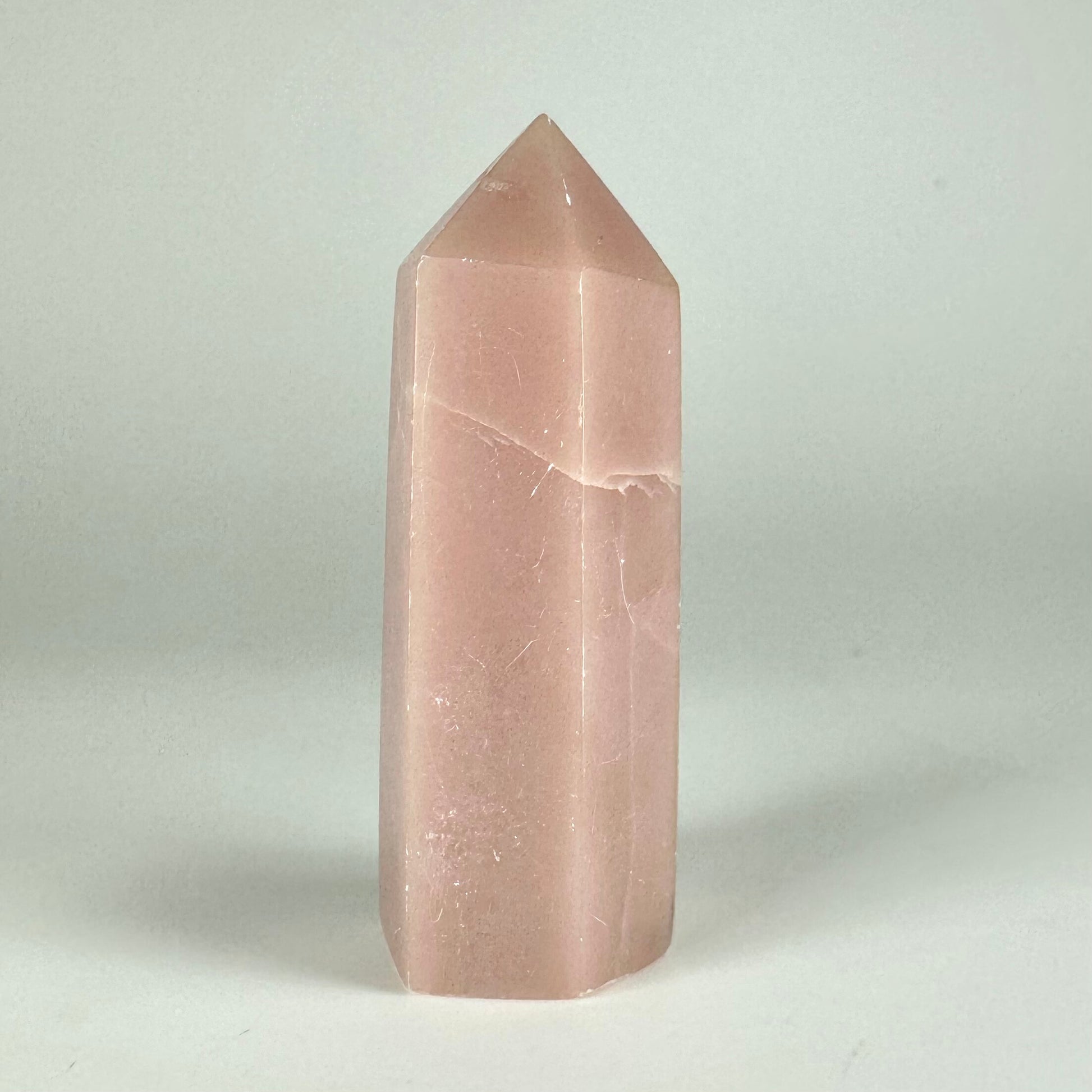 Pink opal tårn mod en grå baggrund, der fremhæver dets bløde nuancer og glatte overflade.