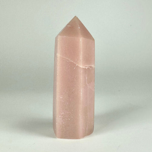 Pink opal tårn mod en grå baggrund, der fremhæver dets bløde nuancer og glatte overflade.
