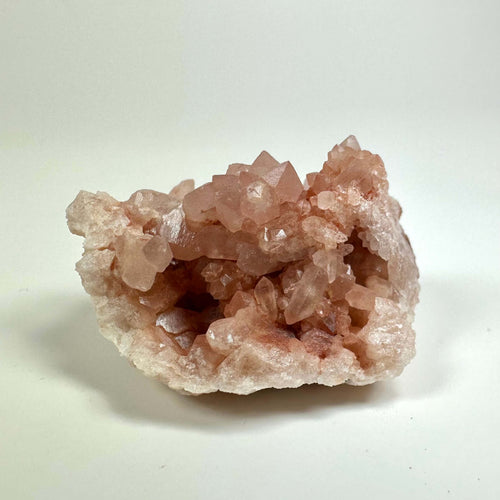 Pink ametyst geode med lyserøde krystaller på en lys baggrund.