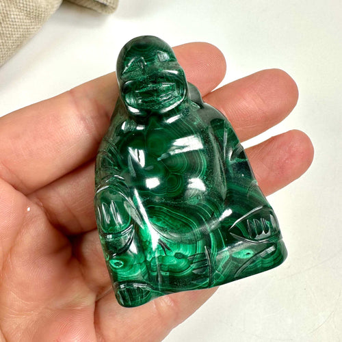 Malakit Buddha-figur holdt i en hånd med indviklede detaljer og dybgrønne nuancer.