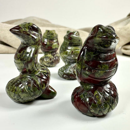 Stenfigurer af Drageblod slanger på hvid baggrund; stof i baggrunden.
