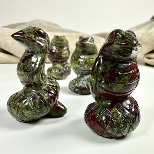 Stenfigurer af Drageblod slanger på hvid baggrund; stof i baggrunden.