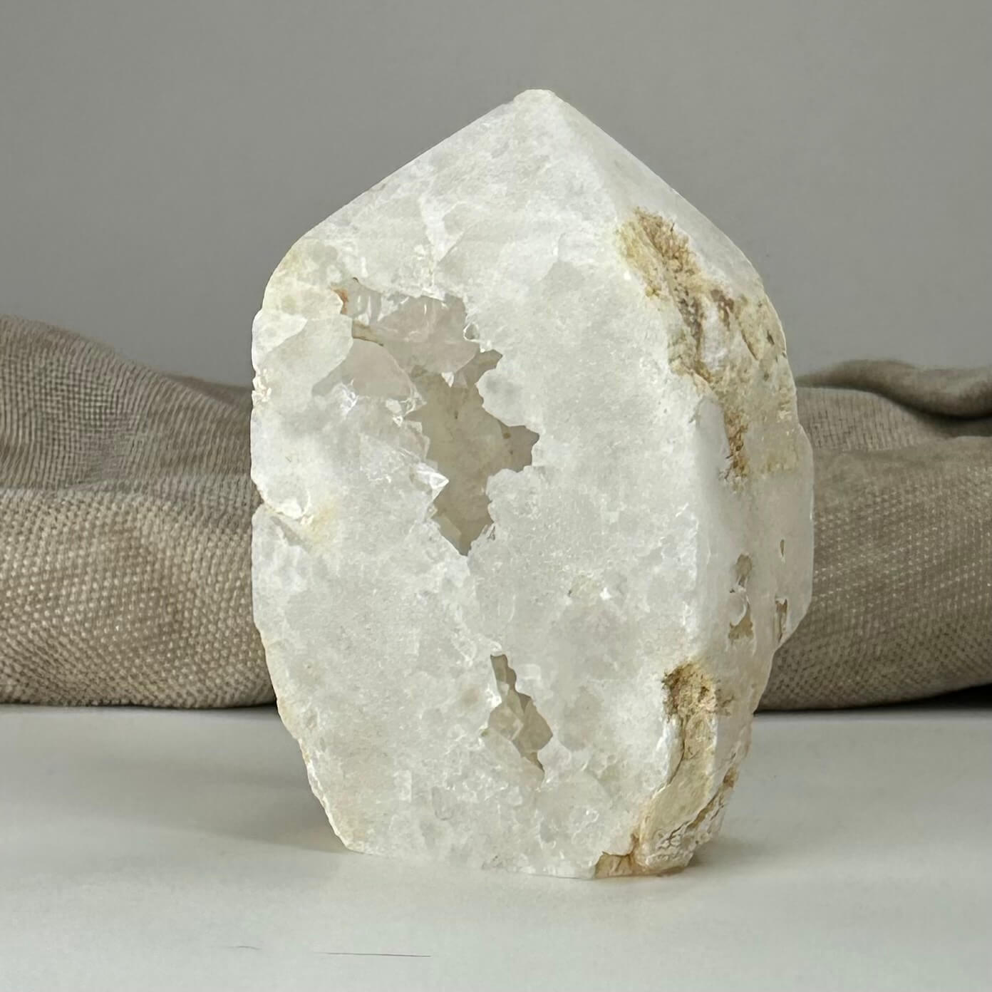 Kvarts geode tårn på en lys overflade foran en beige baggrund.