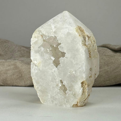 Kvarts geode tårn på en lys overflade foran en beige baggrund.