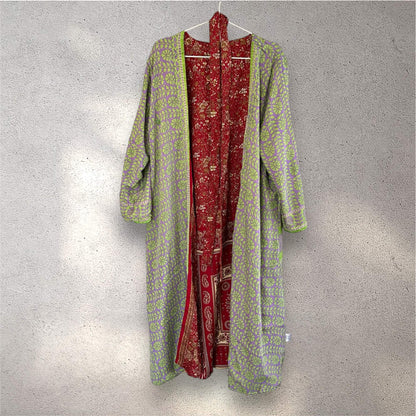 Grøn og rød kimono med mønster, hængende på en væg.