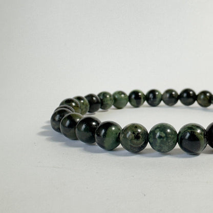 Jaspis Kabamba armbånd i mørkegrønne nuancer på en lys baggrund.